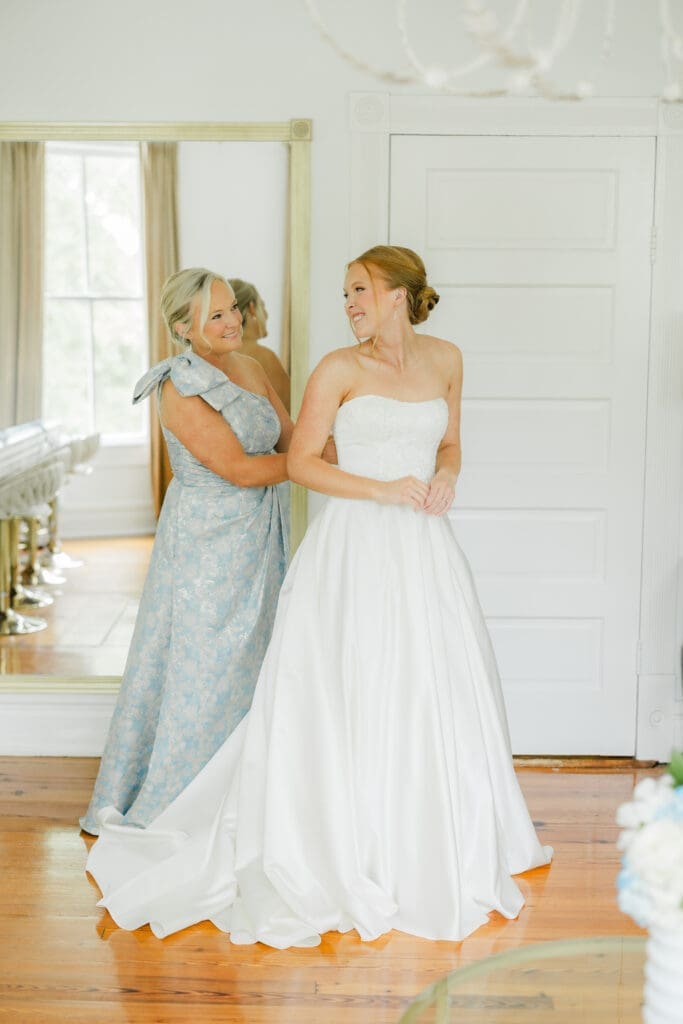 Bride putting on dress with mom before wedding ceremony in Birmingham Alabama