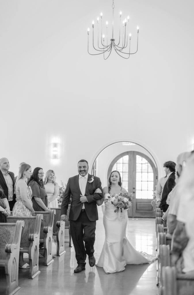 Bride walking down the aisle in white chapel ceremony