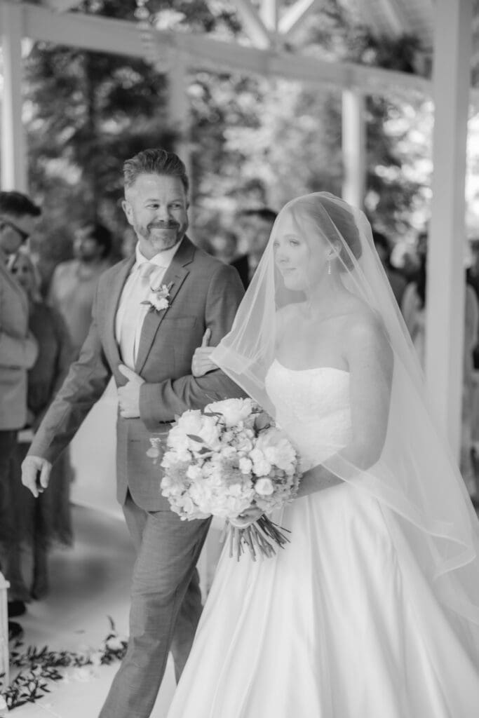 Bride walking down aisle with veil down during wedding ceremony
