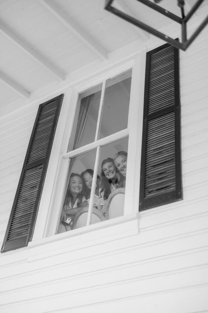 Bridesmaids watching emotional first look from upstairs window