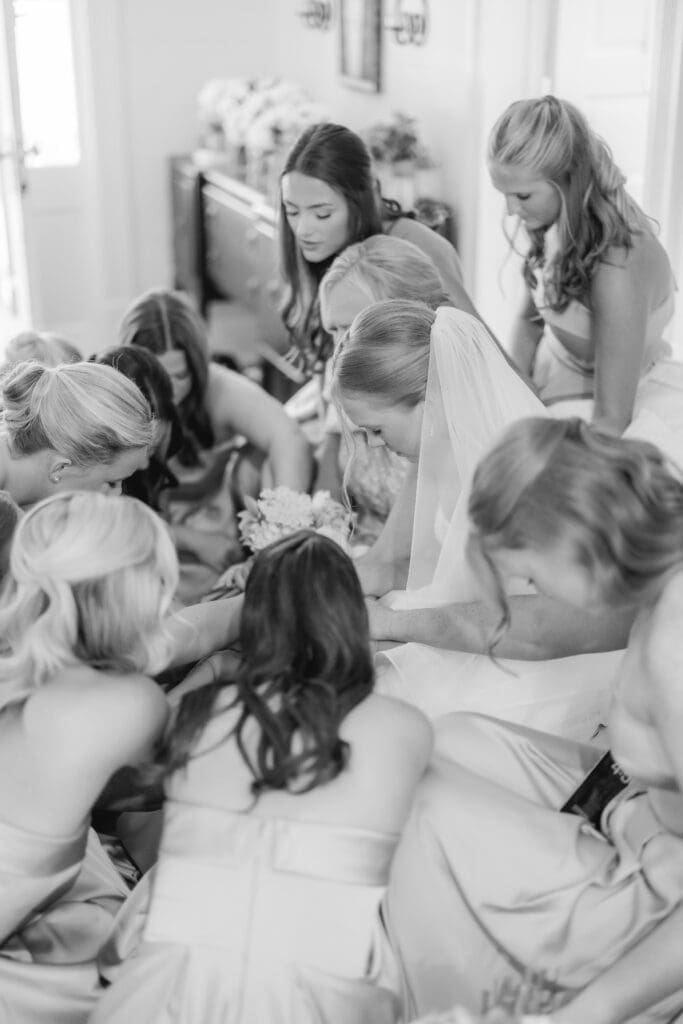 Bridesmaids and mother praying over bride before ceremony
