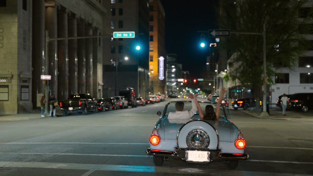 Bride and groom leaving wedding in vintage getaway car
