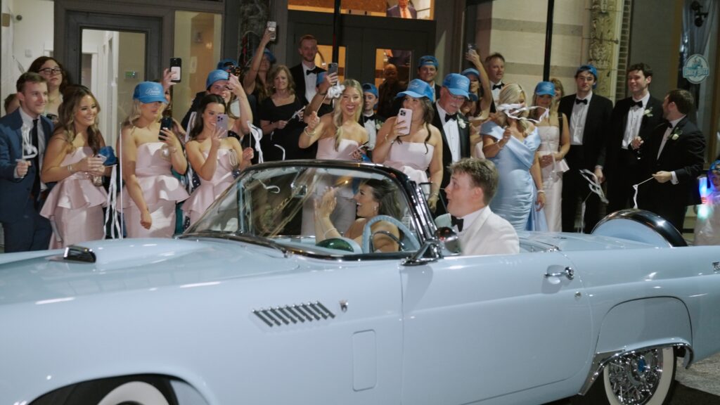 Bride and groom leaving wedding in vintage getaway car