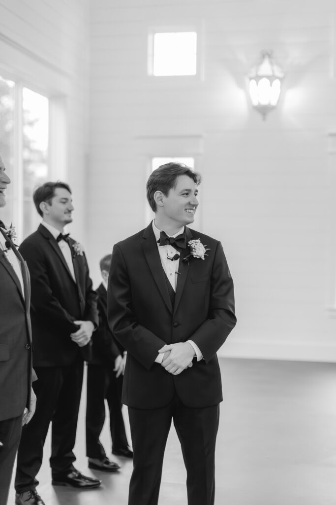 Groom smiling as his bride walks down the aisle at Ridge Pointe.