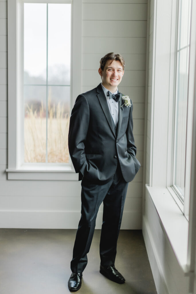Groom looking out the window before her January wedding ceremony at Ridge Pointe.