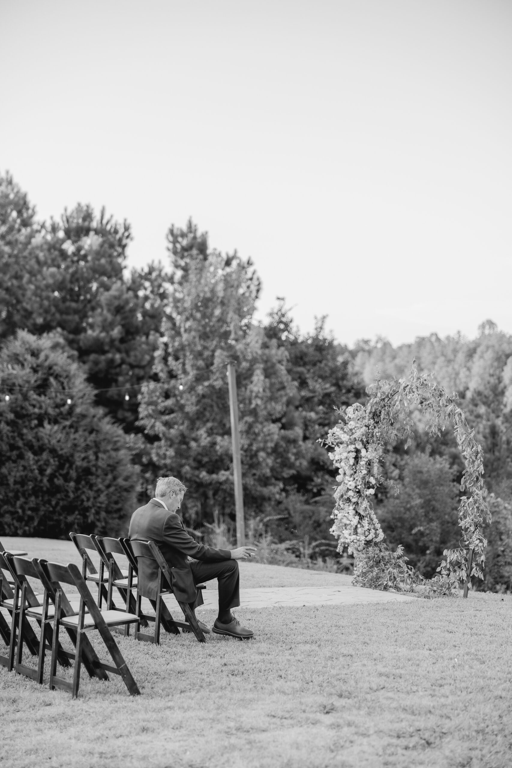 Bride's father sitting alone after the wedding ceremony at The Barn at Smith Lake