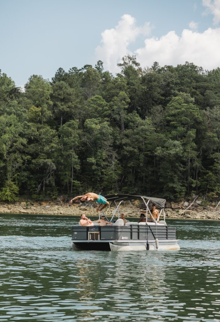 Friends jumping off a boat during a destination wedding weekend at Smith Lake