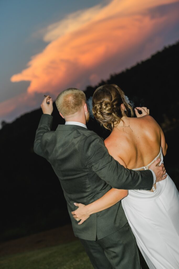 Bride and groom smoking a cigar with sunset at The Barn at Smith Lake