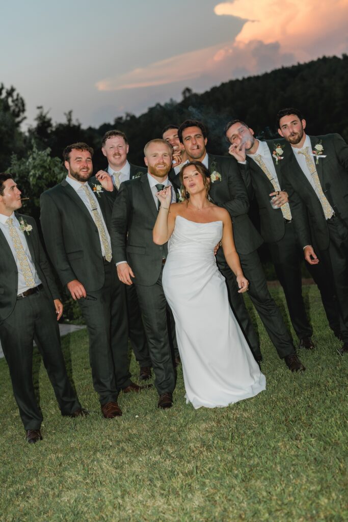 Bride Jess smoking a cigar with her wedding party at The Barn at Smith Lake