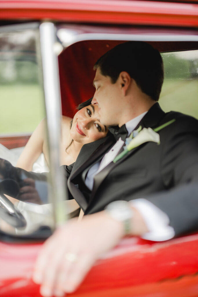 Abby and Jonathan sitting together in a vintage red pickup truck during sunset portraits.
